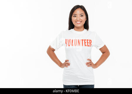 Portrait of a happy smiling asian woman in t-shirt debout avec les mains sur les hanches et à l'écart isolé sur fond blanc Banque D'Images