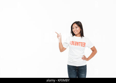 Portrait of a smiling woman joyeux en t-shirt et en pointant du doigt à big copie espace isolé sur fond blanc Banque D'Images
