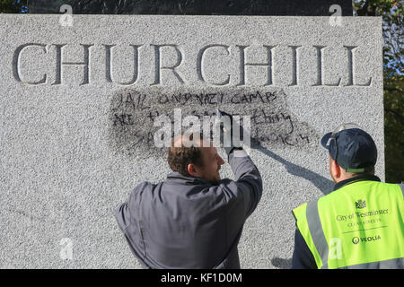 Londres, Royaume-Uni. 25 octobre, 2017 Conseil de Westminster. unité anti graffiti laver et nettoyer les graffiti à l'écrit encore lisible ''la prison et les camps nazis sont la même chose" sur la statue de sir Winston Churchill en face du palais de Westminster laissés par les manifestants de la jungle de calais le jour précédent. crédit : amer ghazzal/Alamy live news Banque D'Images