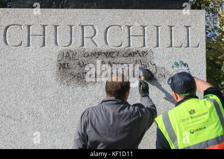 Londres, Royaume-Uni. 25 octobre, 2017 Conseil de Westminster. unité anti graffiti laver et nettoyer les graffiti à l'écrit encore lisible ''la prison et les camps nazis sont la même chose" sur la statue de sir Winston Churchill en face du palais de Westminster laissés par les manifestants de la jungle de calais le jour précédent. crédit : amer ghazzal/Alamy live news Banque D'Images