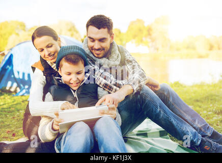 Famille heureuse avec tablet pc et tente au camp site Banque D'Images