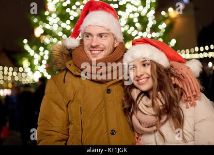 Couple heureux dans santa hats at Christmas Tree Banque D'Images