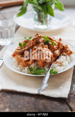 Lave riz au bœuf stroganoff sur une plaque blanche. Banque D'Images