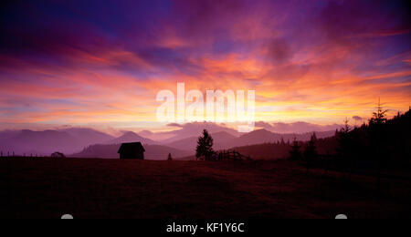 Beau coucher de soleil alpin avec sapins et chalet Banque D'Images