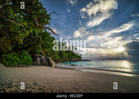 Coucher du soleil sur la plage pittoresque de rêve à anse georgette sur Praslin sur les seychelles. Un gros rocher de granit, l'eau turquoise, des palmiers et un ciel romantique.. Banque D'Images