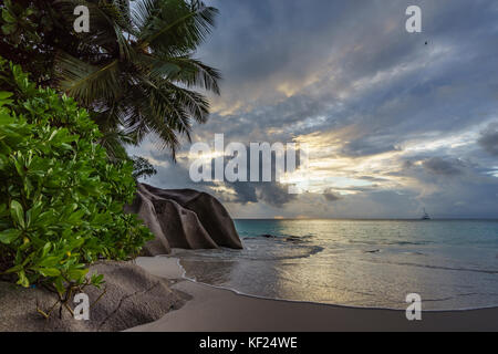 Coucher du soleil sur la plage pittoresque de rêve à anse georgette sur Praslin sur les seychelles. Un gros rocher de granit, l'eau turquoise, des palmiers et un ciel romantique.. Banque D'Images