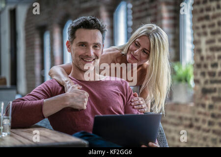 Couple heureux antennes en country house cuisine, looking at laptop Banque D'Images