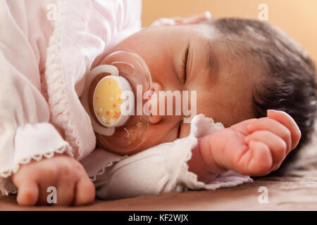 Close up portrait of a cute deux semaines Naissance bebe Fille portant des vêtements en tricot rose tendre, dormir paisiblement avec une tétine, sucette ou factice aka Banque D'Images