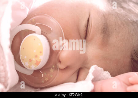 Close up portrait of a cute deux semaines Naissance bebe Fille portant des vêtements en tricot rose tendre, dormir paisiblement avec une tétine, sucette ou factice aka Banque D'Images