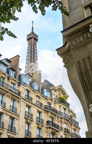 Le haut de la Tour Eiffel vu d'en bas de la rue avec le feuillage et typique des immeubles d'habitation au premier plan. Banque D'Images