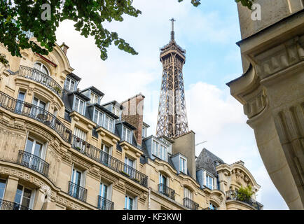 Le haut de la Tour Eiffel vu d'en bas de la rue avec le feuillage et typique des immeubles d'habitation au premier plan. Banque D'Images