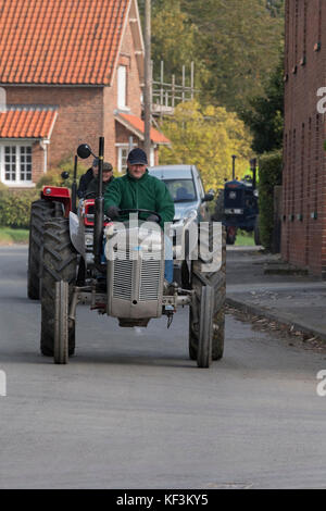 Vintage gris homme conduisant le tracteur en parade dans village Bugthorpe pour événement annuel de bienfaisance - Wolds Groupe Vintage Road Run, Yorkshire, Angleterre, Royaume-Uni. Banque D'Images