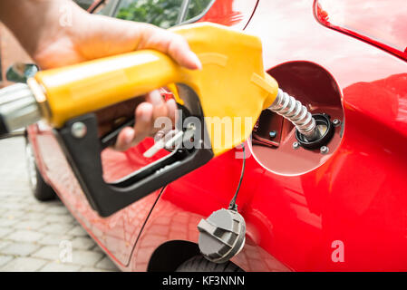 Close-up of woman's hand refueling car la cuve en maintenant la buse de la pompe à essence Banque D'Images