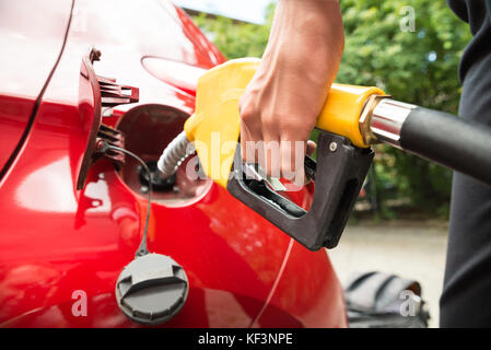 Close-up of woman's hand refueling car la cuve en maintenant la buse de la pompe à essence Banque D'Images