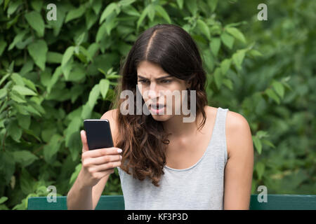 Close-up de jeunes frustrés Woman Looking At Mobile Phone Banque D'Images