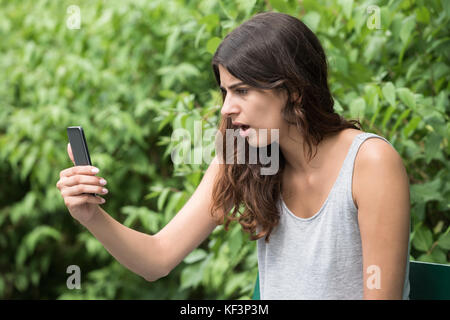 Close-up de jeunes frustrés Woman Looking At Mobile Phone Banque D'Images