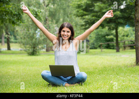 Young Happy Woman Sitting on Green Grass In Park Banque D'Images