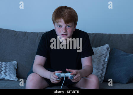Boy sitting on sofa at home les jeux vidéo Banque D'Images