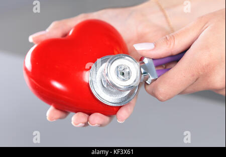 Femme médecin tenir en mains jouet rouge coeur et stéthoscope. cardio- thérapeute, concept d'arythmie Banque D'Images