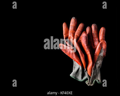 Revêtement de caoutchouc orange usé sale gants de travail sur noir Banque D'Images