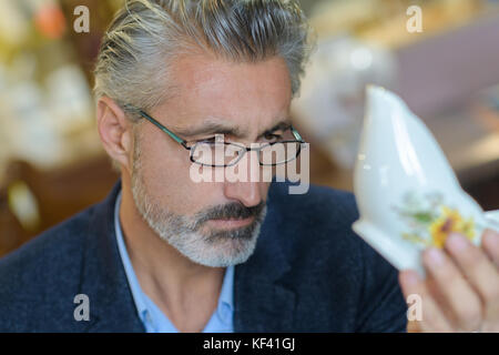 L'homme l'inspection d'un petit vase Banque D'Images