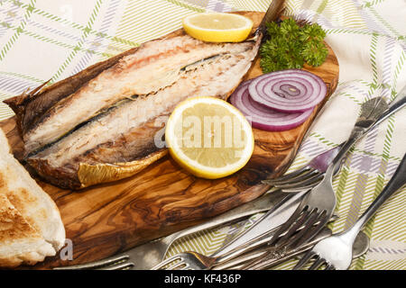 Maquereau fumé sur une planche en bois avec des rondelles de citron, l'oignon violet et griller le pain Banque D'Images