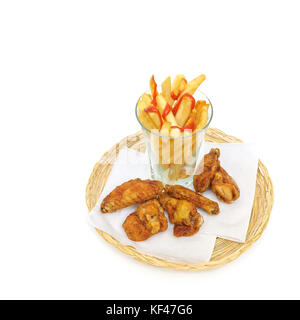 Tranches de pommes de terre frites les frites dans un verre et pilons de poulet frit et les ailes sur une serviettes de papier dans un panier en osier ou le pain blanc sur Banque D'Images