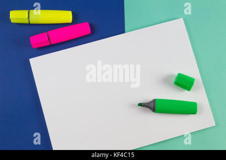 Jaune, rose et vert surligneurs marqueurs avec feuille de papier blanc sur fond coloré. Banque D'Images