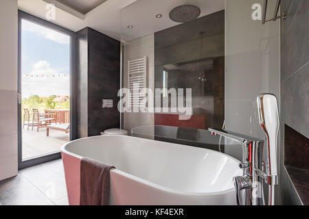 Salle de bains luxueuse avec grande baignoire et porte du balcon Banque D'Images