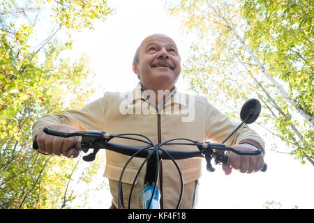 Young man sur balade en vélo dans la campagne. Vert des arbres sur l'arrière-plan. Il est heureux et actif. Banque D'Images