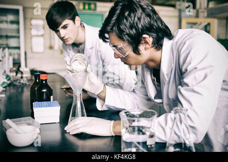 Les élèves de sexe masculin faisant une expérience de chimie en laboratoire Banque D'Images