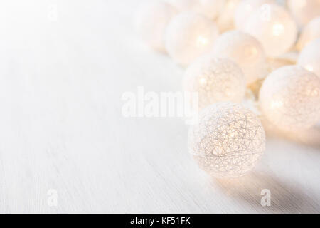 Boule de coton blanc garland avec lumières scintillantes sur bois table. pastel. nouvel an noël décoration ornement copie image minimalistes. Banque D'Images