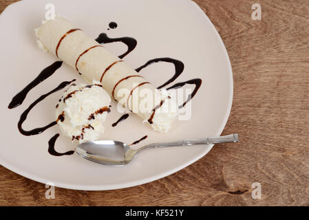 Vue de dessus de la crème glacée à la vanille avec sauce au chocolat crêpe et cuillère Banque D'Images