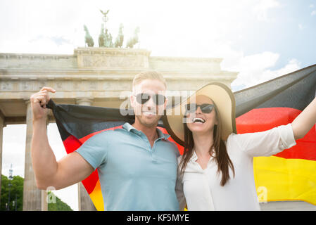 Smiling young couple holding flag, à la porte de Brandebourg Banque D'Images