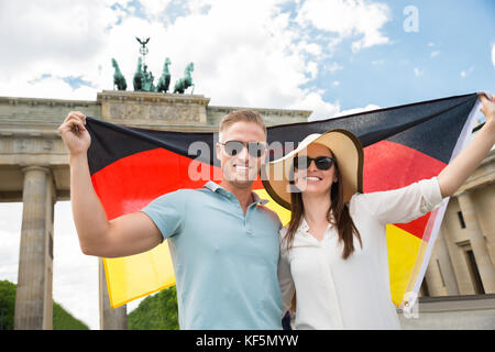 Smiling young couple holding flag, à la porte de Brandebourg Banque D'Images