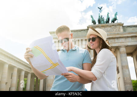 Jeune couple Looking At Map en face de la porte de Brandebourg Banque D'Images