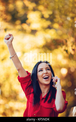 Heureux happy young woman listening de très bonnes nouvelles sur smartphone et être très heureux à l'automne la nature. Banque D'Images