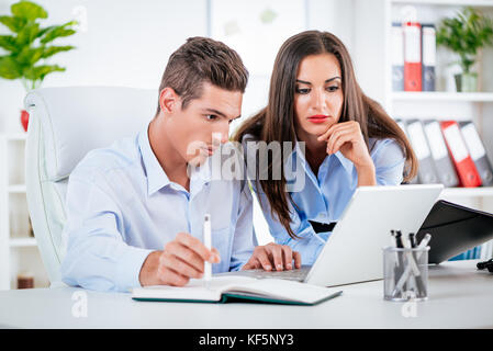 Les jeunes gens d'affaires travaillant sur le comprimé dans l'office. Banque D'Images