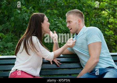 Young Couple Sitting on Bench se quereller les uns avec les autres au Parc Banque D'Images