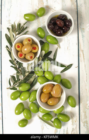 Trois types d'olives et olives brutes fraîches avec de jeunes branche d'olivier sur fond de bois vieux Banque D'Images