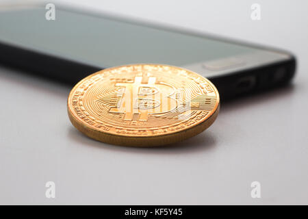 Un téléphone intelligent et bitcoin sur une surface isolée blanc Banque D'Images