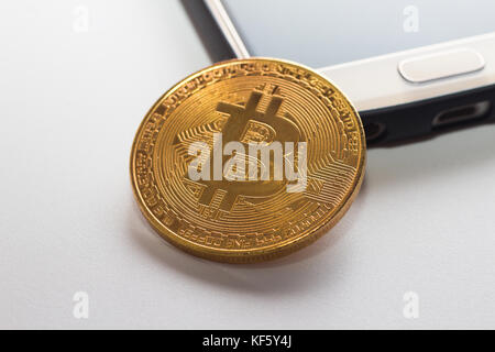 Un téléphone intelligent et bitcoin sur une surface isolée blanc Banque D'Images