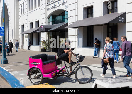 San Francisco, Californie, USA - Septembre 13th, 2017 : un pedicab est en attente pour les passagers tout en est à son portable à alcatraz landing café. Banque D'Images