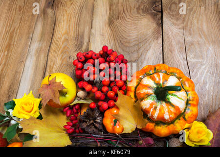 Arrière-plan de récolte d'automne avec des citrouilles, pommes, fruits rouges et fleurs jaunes sur la table de bois rustique, copy space Banque D'Images