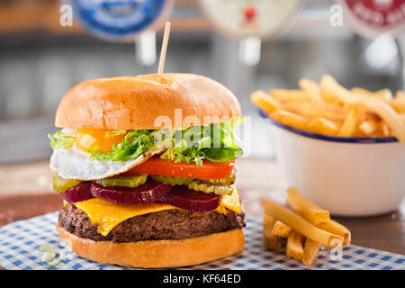 Burger de boeuf au fromage, laitue, tomate, betterave & cornichon, surmonté d'un œuf frit Banque D'Images