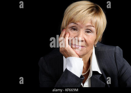 Portrait d'une femme âgée (70 +) dans un costume d'affaires sur un arrière-plan sombre close-up Banque D'Images