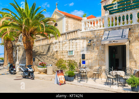 SPLITSKA VILLAGE, l''île de Brac - SEP 7, 2017 : Les Tables d'un café local en face d'une église à Supetar port, l''île de Brac, Croatie. Banque D'Images