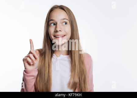 Smiling teenage girl pointe vers le haut avec son doigt Banque D'Images