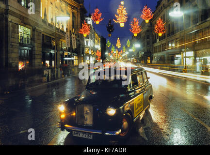Un taxi noir à Regent Street Londres pendant la saison des fêtes, les lumières de Noël. L'Angleterre. UK Banque D'Images