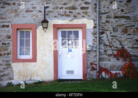 Des toilettes publiques dans un cottage nostalgique d'une façade en pierre et d'une lanterne. Banque D'Images